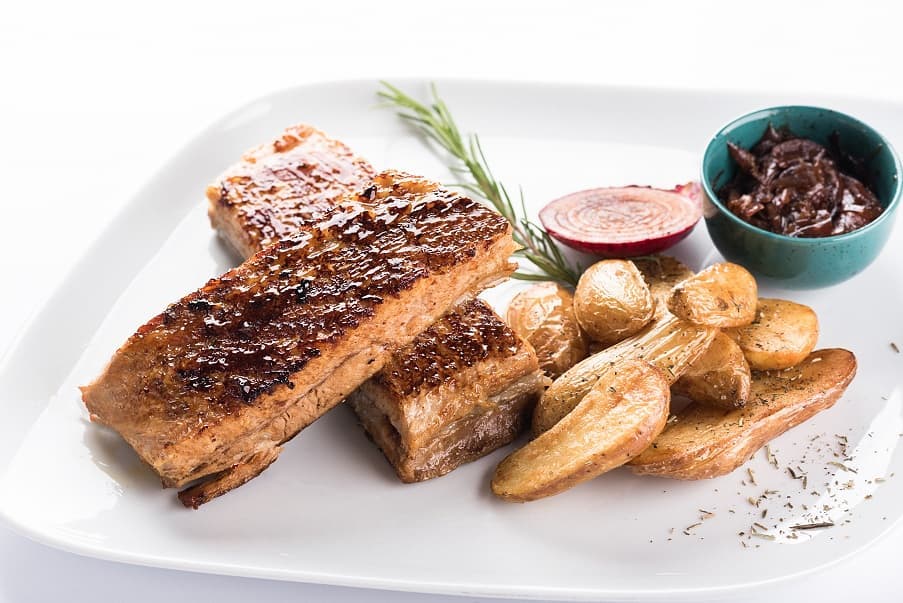 Två grillade revbensspjäll med ugnsrostad potatis, rödlök, rosmarin och sås - idealisk måltid för fiskeresa eller sportfiskare.