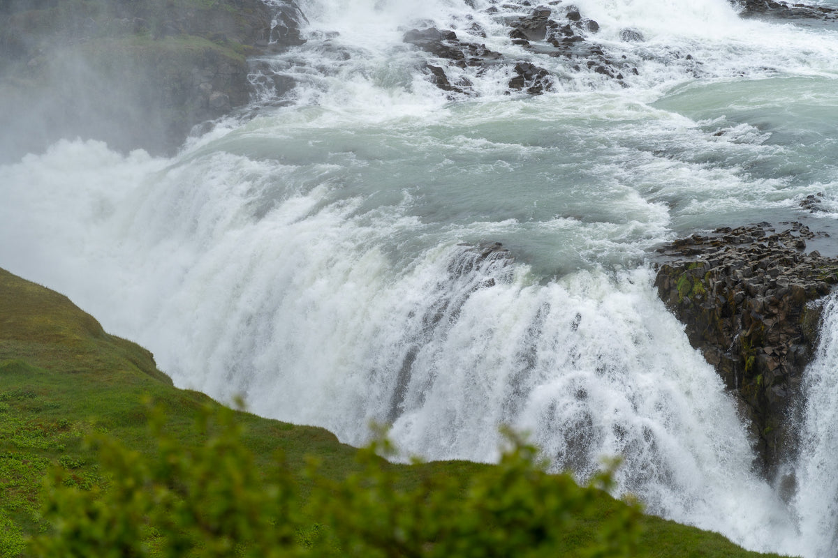 Ett mäktigt vattenfall forsar över klipporna, omgivet av grönska – en perfekt miljö för fiskeresor och spännande fiskeäventyr.