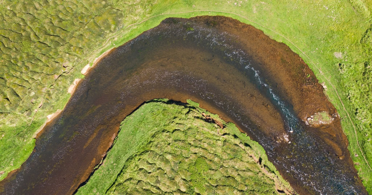 Flygbild över en slingrande älv genom grönt landskap på Island