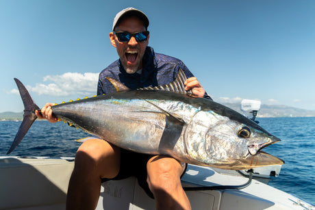 Jublande fiskare med öppen mun visar upp en stor blåfenad tonfisk i båten i Spanien