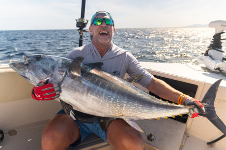 Skrattande fiskare håller en stor blåfenad tonfisk i båten med glittrande hav – tonfiskfiske i Spanien